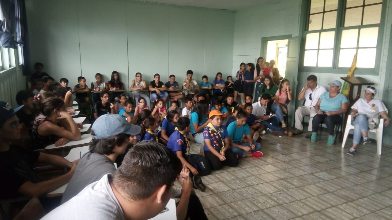 Numeroso grupo de niñas, niños y jóvenes sentados en un salón, durante una reunión