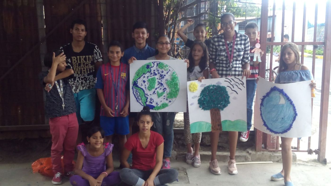 Niñas, niños y jóvenes sostienen carteles pintados a mano con la Tierra, un árbol y una gota de agua